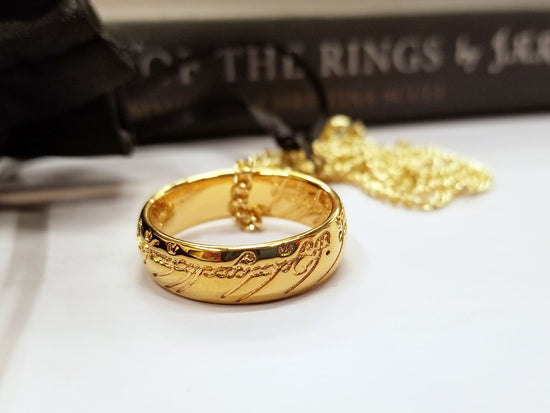 Load image into Gallery viewer, The One Ring, also called The Ruling Ring and Isildur&amp;#39;s Bane, is crafted in solid bronze by the Badali Jewelry artists and then barrel plated with pure 24k gold. Each One Ring pendant has the appearance of solid gold, hence the name, Gollum Gold. Our Gollum Gold One Ring appeared in an episode of The Big Bang Theory. 

