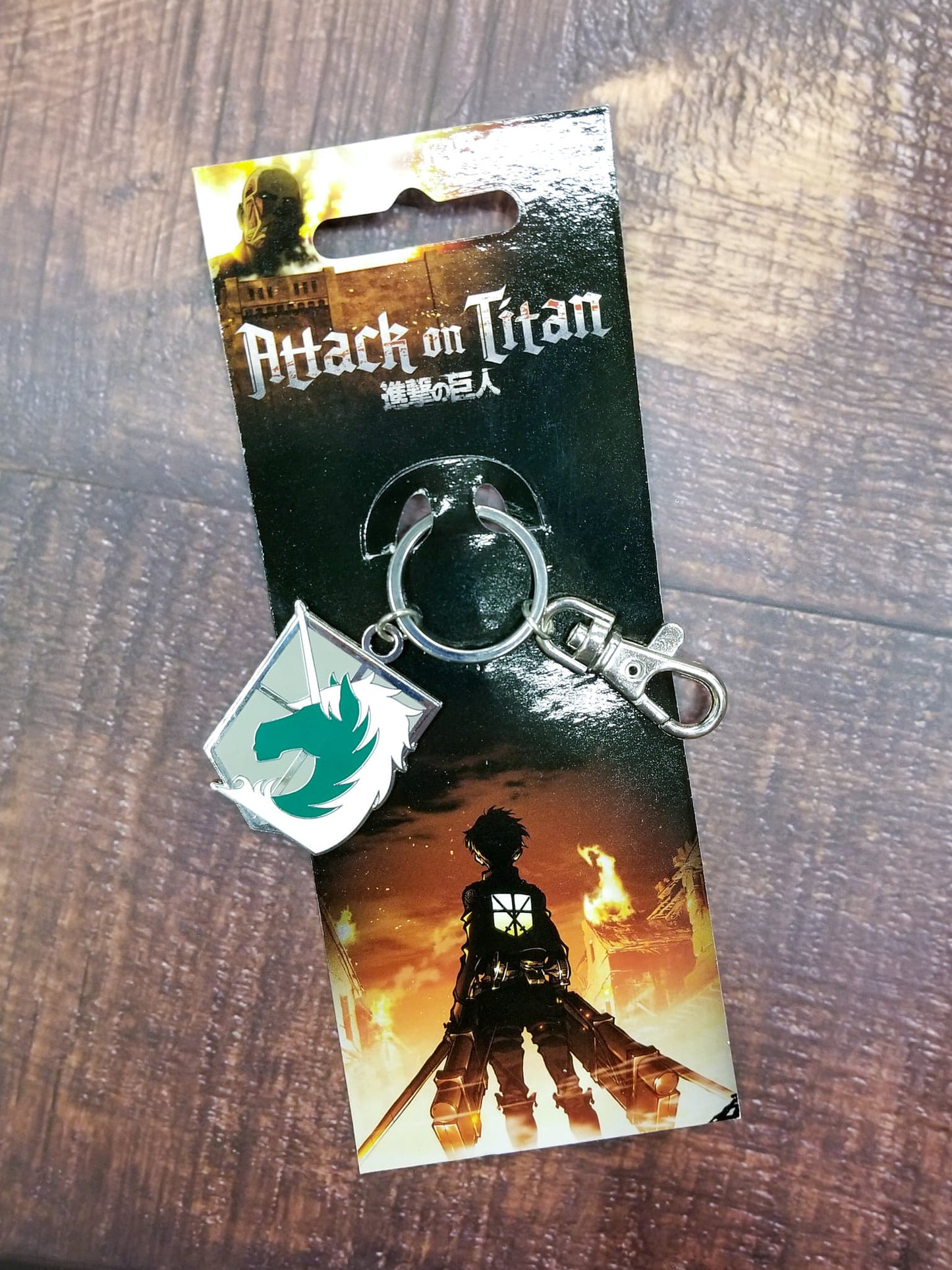 Load image into Gallery viewer, An enameled metal keychain with clip and ring, depicting the Military Police Brigade emblem from Attack on Titan.  The metal emblem is approximately 1 inch wide by 1.5 inches tall.
