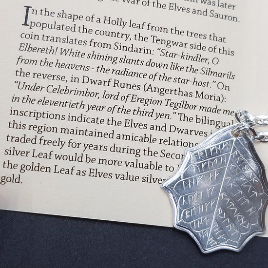 This Elvish Mithril Leaf of Spring Necklace is crafted in celebration of The Lord of the Rings by J. R. R. Tolkien. The leaf-shaped coin is struck from solid silver, measures 2.7 cm in diameter, and weighs about 6.5 grams. Includes a 30" antique bronze cable chain with clasp. Coin artwork by Greg Franck-Weiby.  Coins are struck one at a time in the USA using antique machinery and traditional coining techniques. A colorful description is included with history, translations, and facts about the coins.