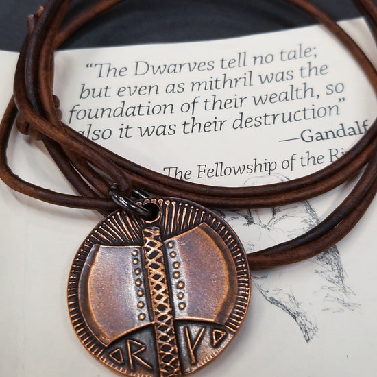 Load image into Gallery viewer, Dwarven Axe of Durin coin pendant necklace from the The Lord of the Rings by J. R. R. Tolkien is struck from solid copper. It is presented on a 30&amp;quot; leather cord. Coin artwork by Greg Franck-Weiby.  This coin is treated to look as if they have been handled and circulated. This process is done by hand, and it is both an art and a science. Coloring and patinas will vary. No two coins are exactly the same! Coins are struck one at a time in the USA using antique machinery and traditional coining techniques. 
