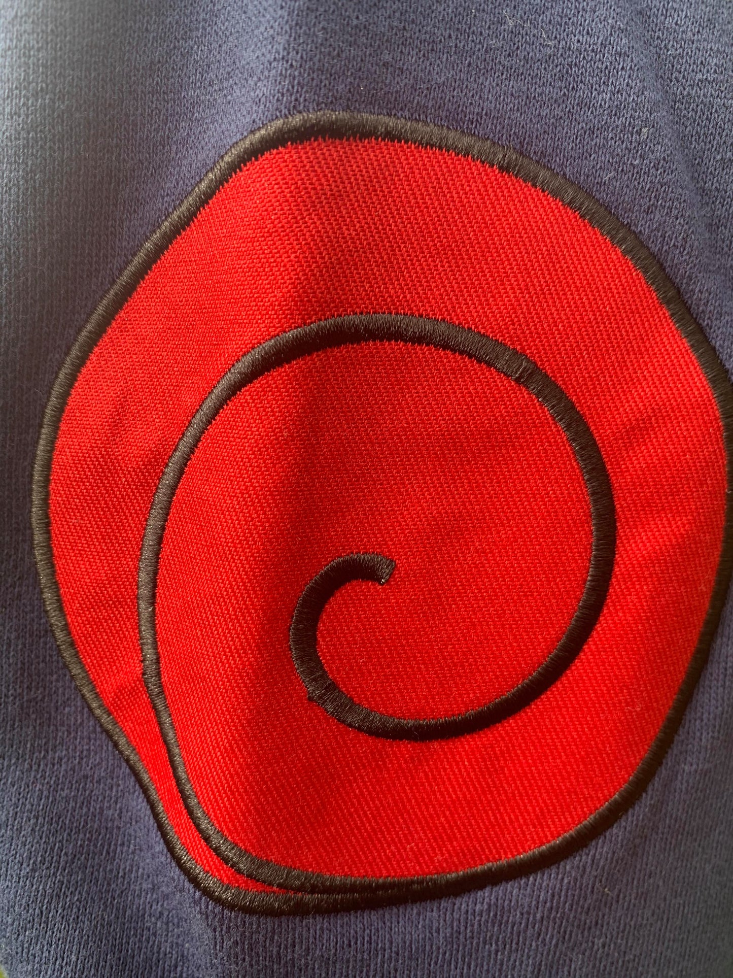 Officially Licensed Naruto Shippuden Military Style Kakashi Hoodie — a cozy zipper sweatshirt with incredible detail work including the Leaf Village emblem and the red swirl Uzumaki Clan Symbol.    Officially Licensed 60/40% Cotton Polyester Machine washable